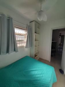 卡庞达卡诺阿Apartamento em Capão Novo com piscina的一间卧室设有一张绿色的床和一个窗户。