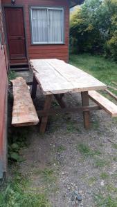 普孔Cabaña Agradable的木屋前的木餐桌和长凳