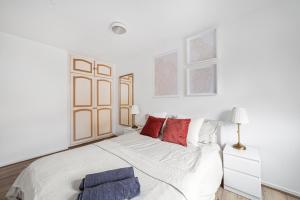 伦敦Arte Stays - 3-Bedroom Bright House London, Haggerston, Garden, Parking, 8 min walk to Haggerston Station, weekly or monthly stays, serviced accommodation - 7 guests的白色卧室配有一张带红色枕头的大白色床