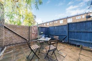 伦敦Arte Stays - 3-Bedroom Bright House London, Haggerston, Garden, Parking, 8 min walk to Haggerston Station, weekly or monthly stays, serviced accommodation - 7 guests的一个带桌椅和围栏的庭院