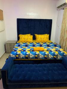Suru LereJesam House的一张蓝色的大床,配有蓝色床头板和黄色枕头