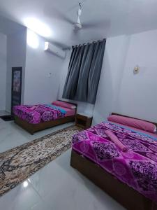 阿斯旺Onaty Narty Guest house的紫色床单的客房内的两张床