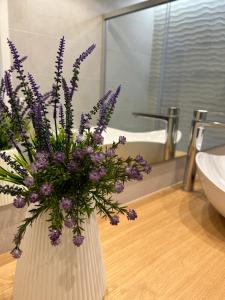 圭马尔港Puertito Beach Suites 1的浴室内一个布满紫色花的花瓶