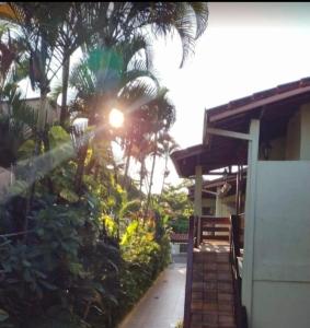 乌巴图巴Ape na Maranduba em frente à praia - Village 5的棕榈树上闪烁的太阳的房子