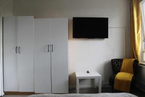 伦敦The Yellow House的卧室配有白色橱柜、电视和椅子。
