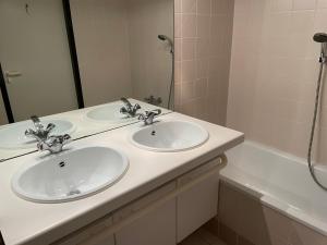 克诺克－海斯特appartement Lichttorenplein met garage的浴室设有2个水槽、镜子和浴缸。