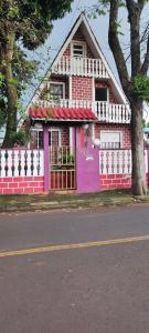 伊瓜苏Quarto privativo的街道前有围栏的粉红色房子