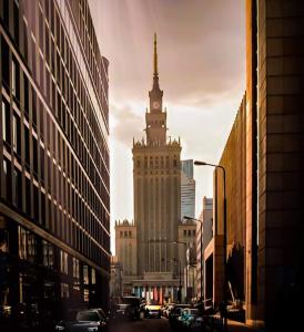 华沙City View Apartment - Zgoda 13的一座高大的建筑,在城市里有一个钟楼