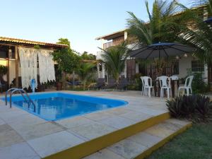 阿奎拉兹Pousada Alecrim的一座房子旁带遮阳伞的游泳池