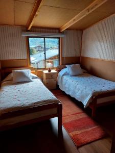 普尤瓦比港Hostal y Cabañas Ventisquero的一间卧室设有两张床和窗户。