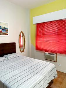 圣维森特岛Apartamento Messi Assú Praia dos Milionários的一间卧室配有一张床和一个带红色百叶窗的窗户