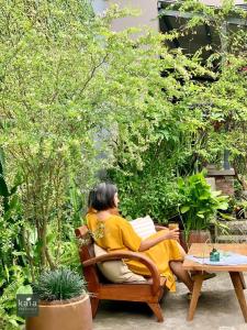 岘港Kaia Residence Danang Quiet Garden的坐在椅子上读书的女人