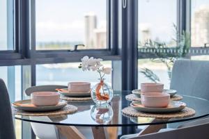 黄金海岸Como Prestige Breathtaking Southport Sundale的玻璃桌,带盘子和杯子,花瓶