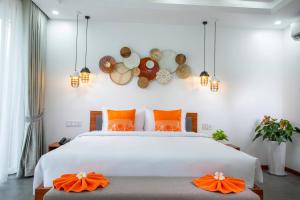 西哈努克Wonderland Suites and Resort的卧室配有带橙色枕头的大型白色床