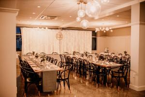 陶朗加阿米蒂奇酒店及会议中心的宴会厅配有桌椅和窗帘