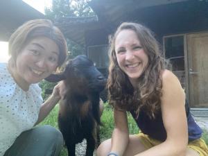 Kizuna Guesthouse的两个女人坐在一只小山羊旁边