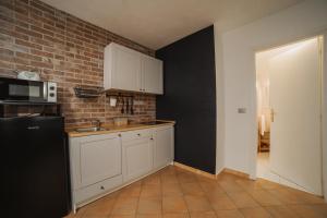 奥斯塔Vevey 5的厨房配有白色橱柜和砖墙