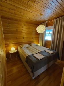 萨利色尔卡Twin Peaks Urupää B Saariselkä的木制客房内的一间卧室,配有一张床