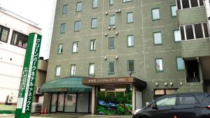 青森Aomori Green Park Hotel Annex的前面有停车位的建筑