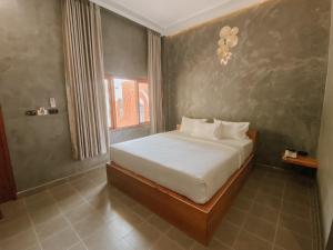 合艾Tachang Airport Hotel的一间卧室配有一张带白色床单的床和一扇窗户。