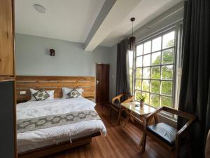 甘托克Bahar Retreat And Spa , Gangtok的一间卧室配有一张床、一张桌子和一个窗户。