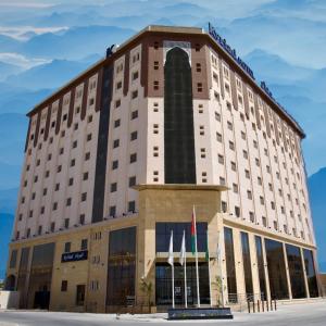 塞拉莱KYRIAD HOTEL SALALAH的前面有旗帜的酒店大楼