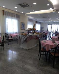 里米尼Hotel Bonaria的用餐室配有桌椅和粉红色的桌布