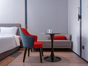 苏州苏州石湖大学城智选假日酒店 的卧室配有1张床、1张桌子和1把椅子