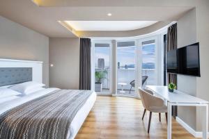 巴统Alliance Palace Batumi的酒店客房配有一张床、一张书桌和一台电视。