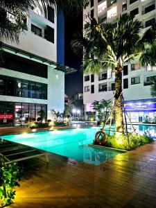 土龙木市C Sky View: 2 BR Apartment Free GYM & POOL的棕榈树在晚上坐在游泳池旁