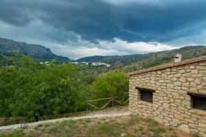 BenisiliCasa Rural Ca Ferminet & Cabañas de montaña La Garriga的一座以山为背景的石头建筑