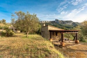 BenisiliCasa Rural Ca Ferminet & Cabañas de montaña La Garriga的石头小屋,在田野上设有野餐桌