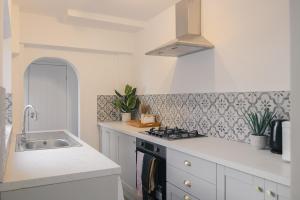 拉格比Newly Refurbished House with Free Parking的白色的厨房设有水槽和炉灶。