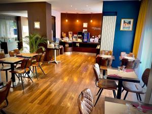 格勒诺布尔格勒诺布尔中心基里亚德酒店的餐厅铺有木地板,配有桌椅