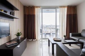 Il- GżiraValletta view Apartments by ST Hotels的带沙发、桌子和电视的客厅