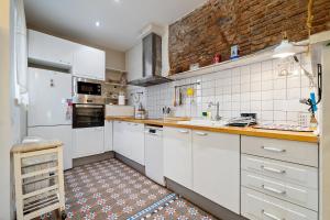 卡里拉Hauzify I Casa d'Anselm Clavé的厨房配有白色橱柜和砖墙