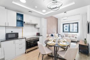 迪拜Nasma Luxury Stays - Home-Style 2BR Apartment with a Balcony View的厨房以及带桌椅的起居室。