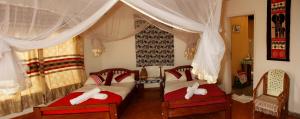 KasenyiEuphorbia Safari Lodge的一间卧室配有两张带红白色枕头的床