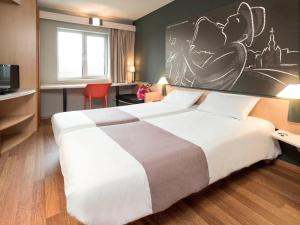 迪南迪南宜必思酒店的酒店客房设有一张大床,墙上挂有绘画作品