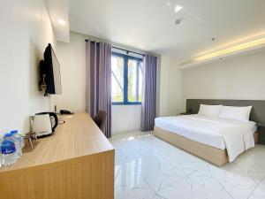朱笃The Luxe Hotel Châu Đốc的配有一张床和一张书桌的酒店客房
