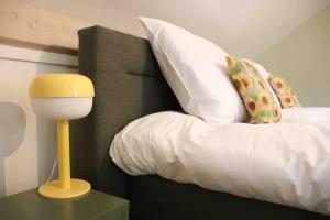 阿布考德GeinLust B&B De Zonnebloem的一张带白色枕头和黄色灯的床