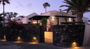 科斯塔特吉塞Bungalow GOA Pool view, Playa Roca residence sea front access - Free AC - Wifi的前面有石墙的房子