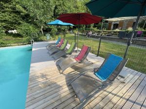 TrocheDordogne et Corrèze vacances - Gites的游泳池旁的一排椅子和一把遮阳伞