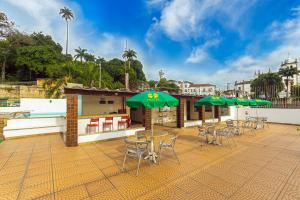 里约热内卢Hotel Golden Park Rio de Janeiro Aeroporto的一个带桌椅和绿色遮阳伞的庭院