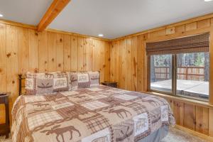南太浩湖Black Bear Hideaway的一间卧室配有一张带木墙和窗户的床。