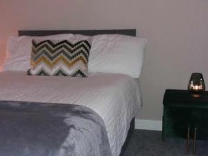 卡里格莱恩Dún Eoin Carrigaline的一间卧室配有一张带枕头和桌子的床