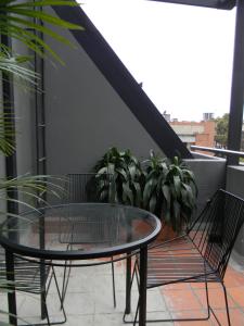 波哥大Soy Local Parque La 93的阳台上的玻璃桌和两把椅子