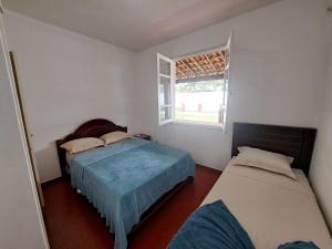 卡波布里奥3 QTS Churrasqueira Garagem perto do Forte e Ilha do Japonês的一间卧室设有两张床和窗户。