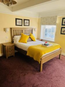 奇平诺顿王冠&靠垫酒店的一间卧室配有一张带黄色枕头的床和一扇窗户