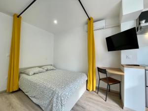 拉格朗德默特cosy douillet la grande motte的一间卧室配有一张带黄色窗帘的床和一张书桌